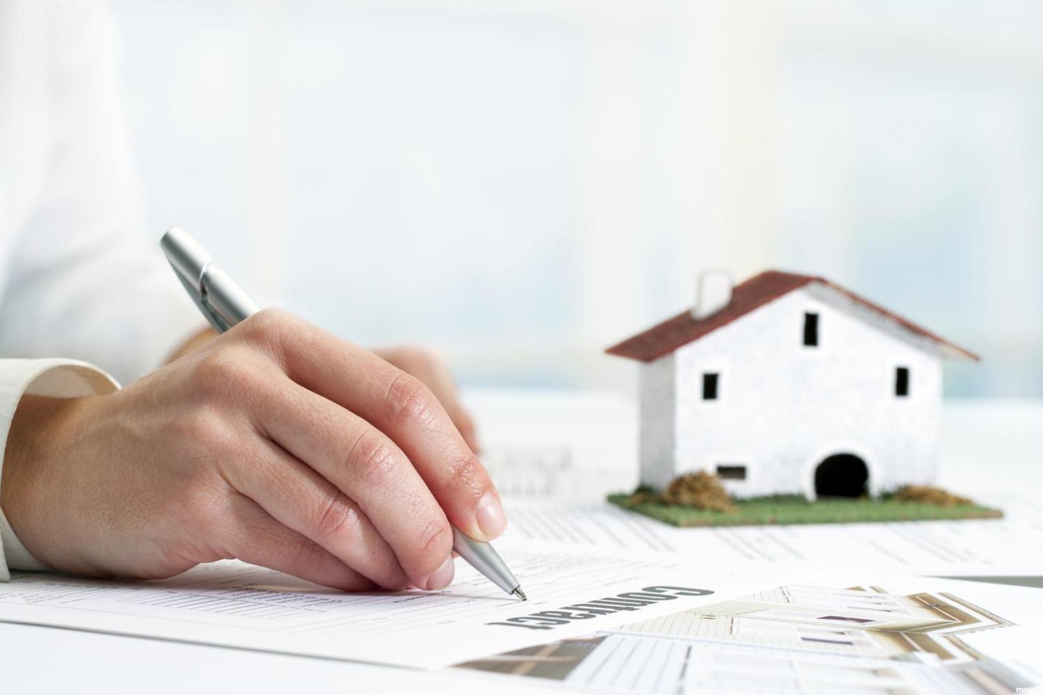 một người đang viết hợp đồng mua bán nhà đất bằng giấy tay