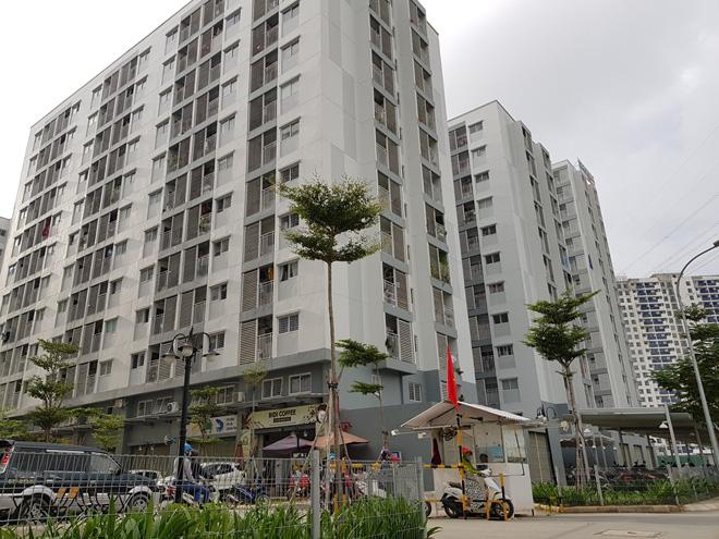 Một chiếc xe ô tô đang đi vào tòa nhà công vụ, bên cạnh là 1 bảo vệ 