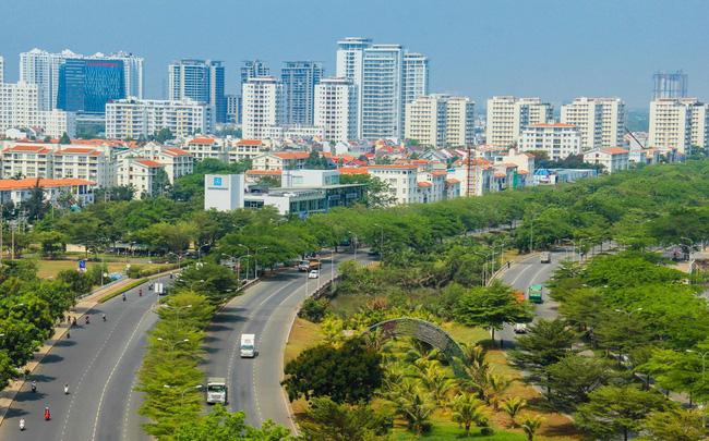 tuyến đường cao tốc có nhiều cây xanh, phía xa có nhiều tòa nhà cao tầng