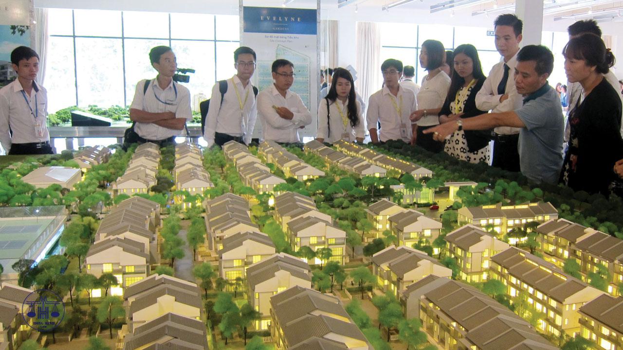 một nhóm người đang đứng xem xét và thảo luận về mô hình dự án nhà ở hình thành trong tương lai