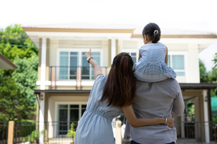 Một gia đình ba người bố, mẹ, con đứng trước ngôi nhà