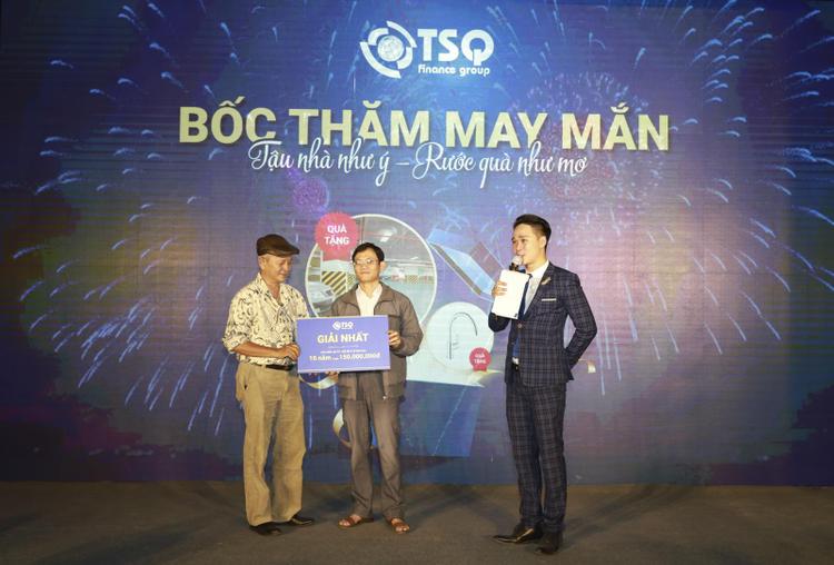 Nam MC đứng giới thiệu và hai người đàn ông cầm tấm bảng ghi dòng chữ giải nhất