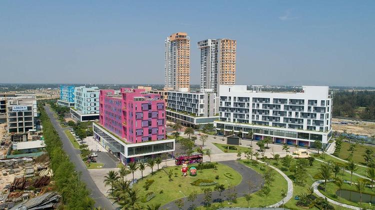 dự án condotel Cocobay Đà Nẵng nhìn từ xa gồm nhiều tòa nhà cao tầng đã xây dựng, có đường đi và cây xanh