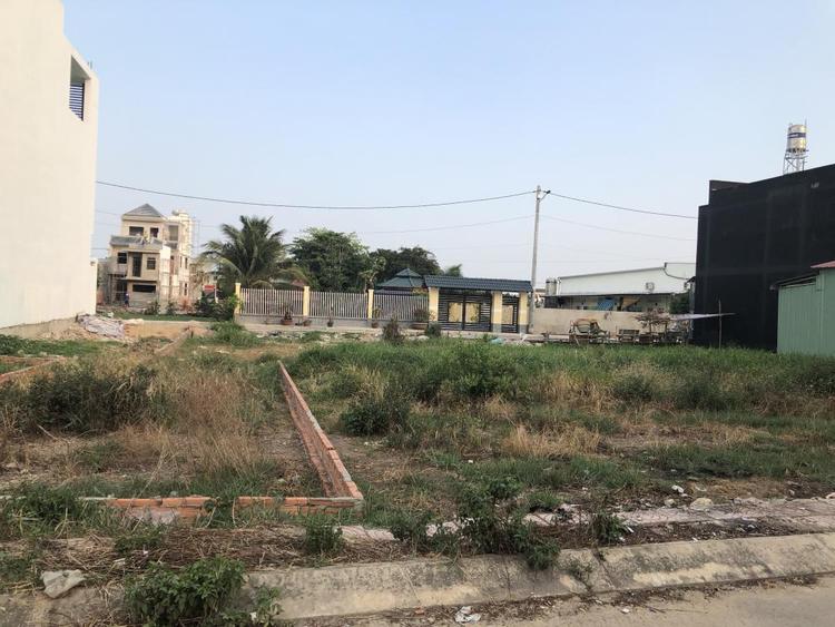 Ảnh chụp một bãi đất trống, bên cạnh là một số công trình nhà ở