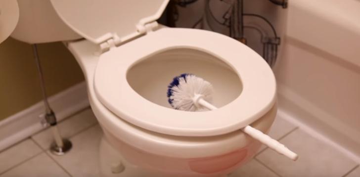 bàn chải toilet được kẹp dưới nắp bồn cầu