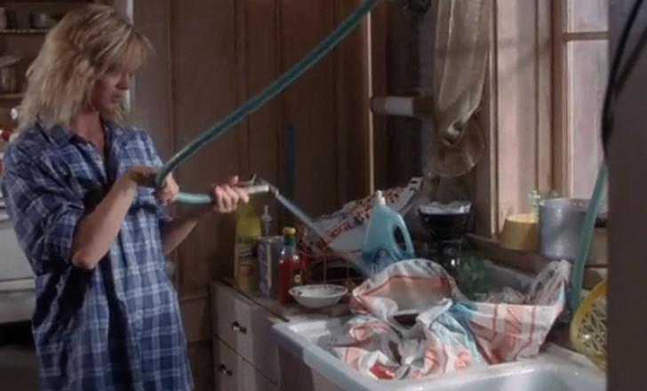 người phụ nữ cầm vòi phun nước nóng trong phòng bếp