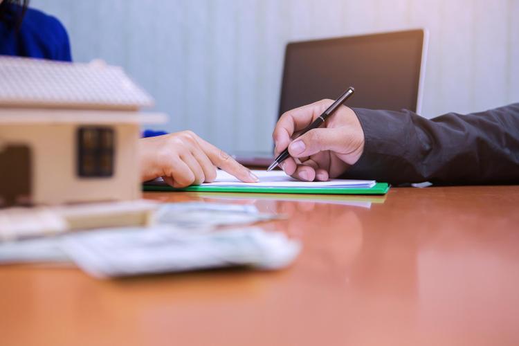 1 bàn tay cầm bút, 1 bàn tay chỉ vào tờ giấy trên bàn