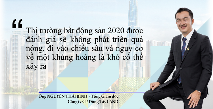 Chân dung một người đàn ông trẻ mặc vest đen đang cười, ngồi trên ghế