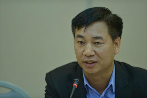 Chân dung người đàn ông trung tuổi mặc vest đen nói trước micro