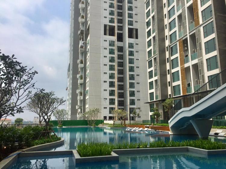 Bể bơi nước xanh trong phía dưới một tòa chung cư cao tầng.