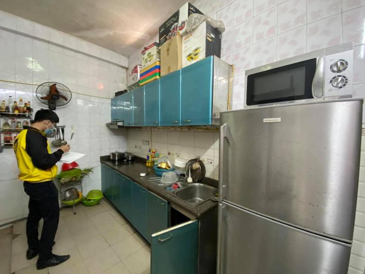 phòng bếp có tủ lạnh, kệ để đồ và người đàn ông đang đứng