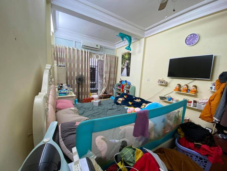 phòng ngủ có giường, tivi và rất nhiều đồ đạc lộn xộn