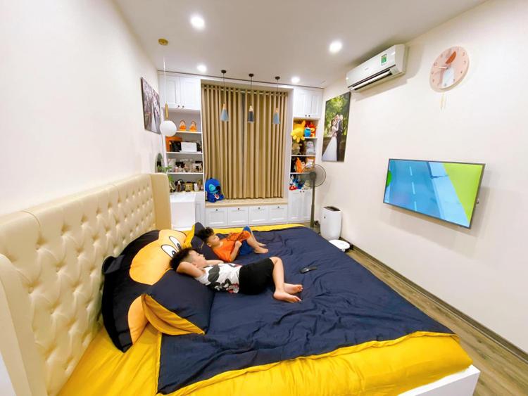 hai đứa bé nằm trên giường xem tivi