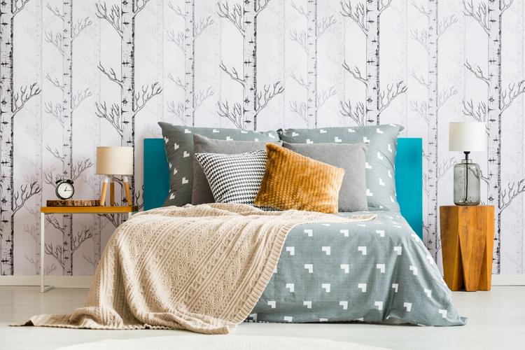 Bed against forest motif wallpaper