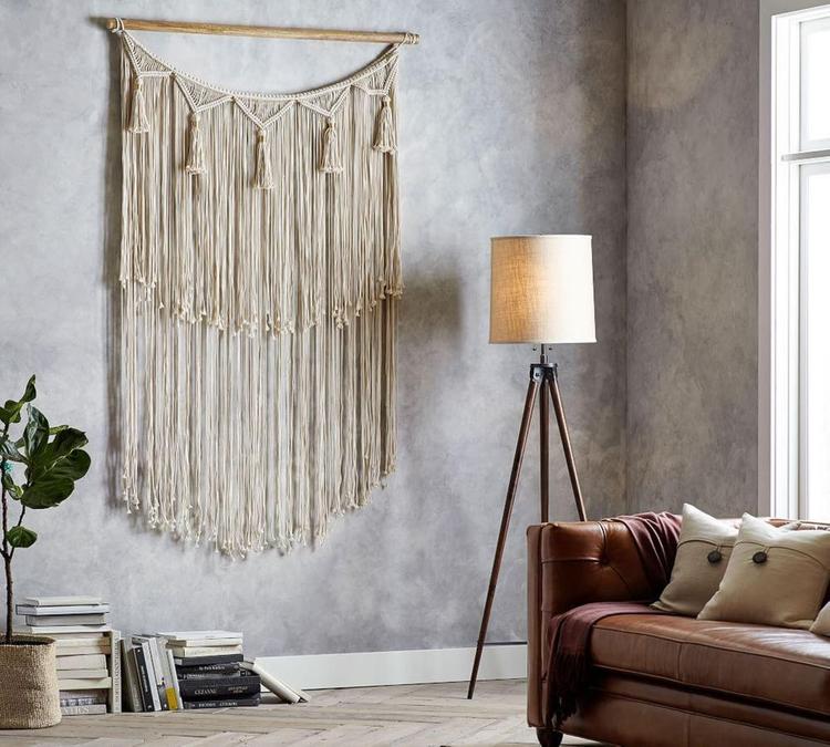 interior with huge macrame hanging on the wall and a brown leather sofa on the side 