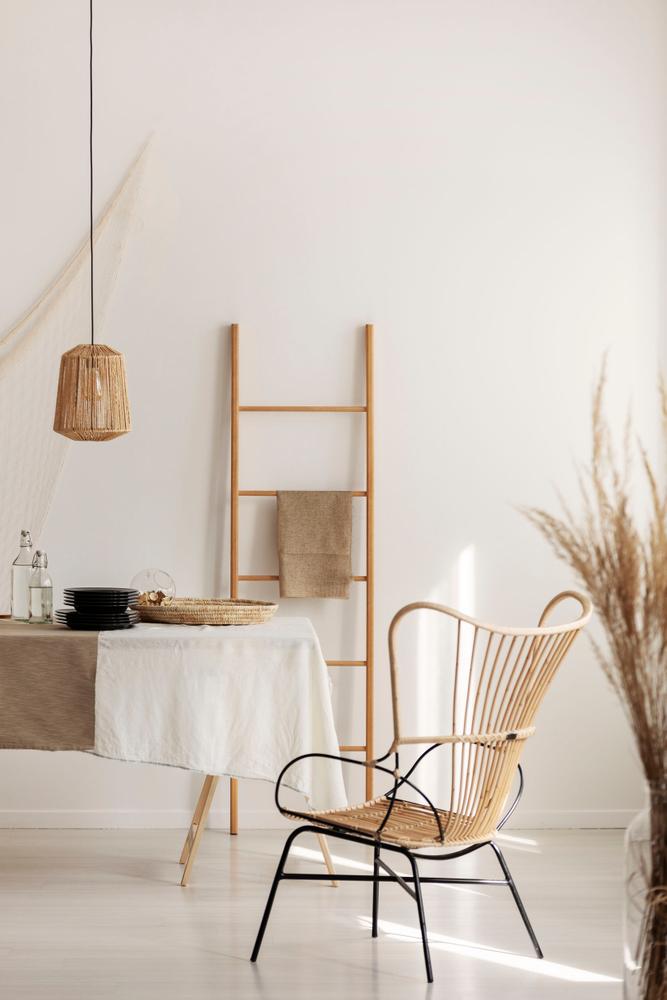 Stylish wicker chairs next to table covered with white table cloth, real photo with copy space on empty wall
