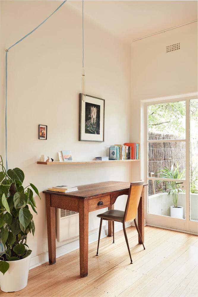 bright room with a study deck, indoor plants, floating shelf and a door to the garden