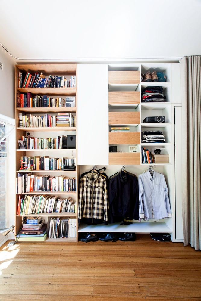 a floor to ceiling shelf filled with books, and clothes