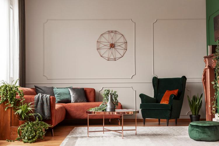 Velvet emerald green armchair with orange pillow next to corner sofa and coffee table interior design