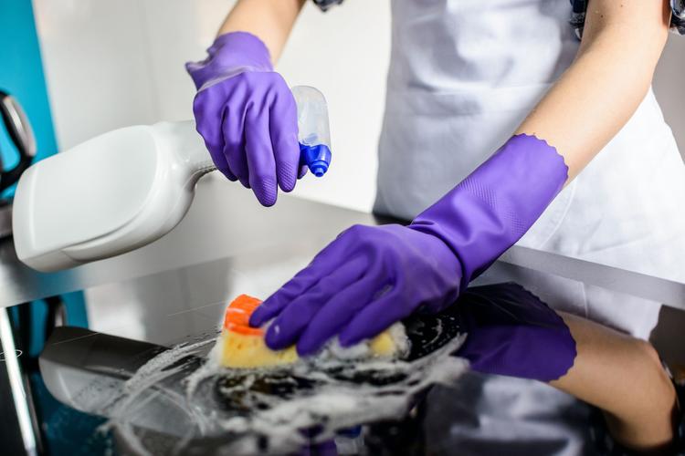 Woman's hands cleaning kitchen top in gloves