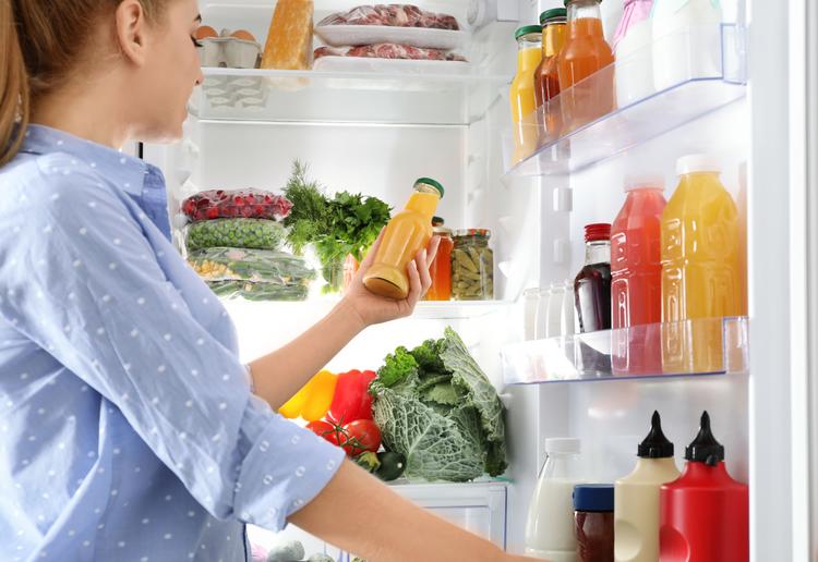 Woman taking bottle with juice out of refrigerator in kitchen