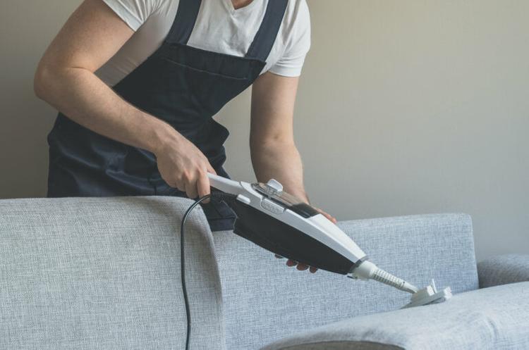 man-cleaning-sofa-using-vacuum
