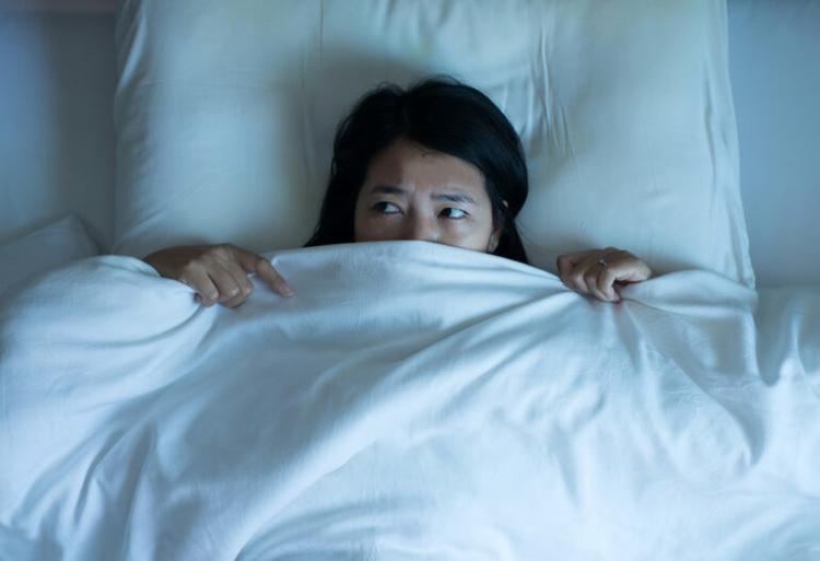 asian-woman-scared-in-bed-hiding-under-sheets