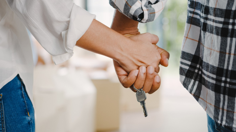 A couple holds hands with a house key