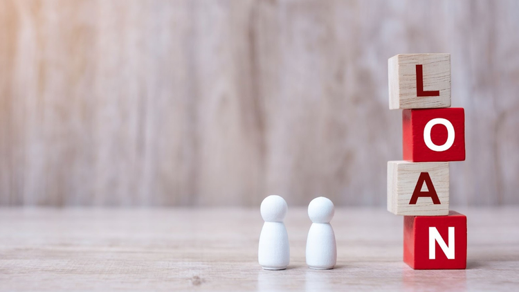 Wooden blocks spelling “loan” with two small figures representing borrowers.