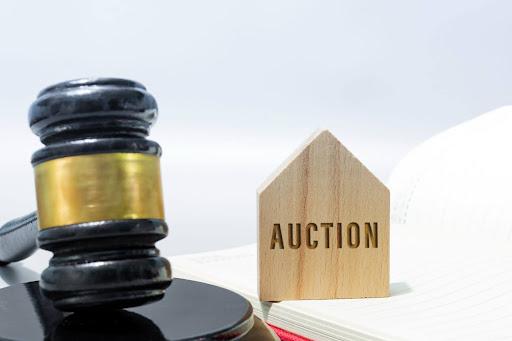 Judge gavel with auction word on a wooden house on a notebook