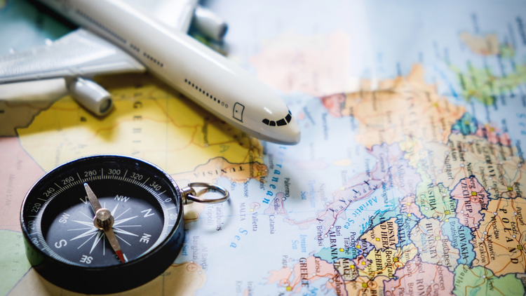 A small toy aeroplane and a compass rest on a colourful map