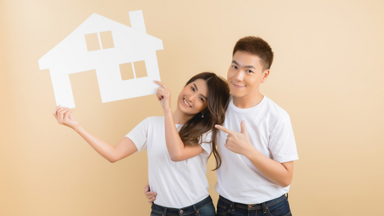Couple holding a white house cutout and smiling