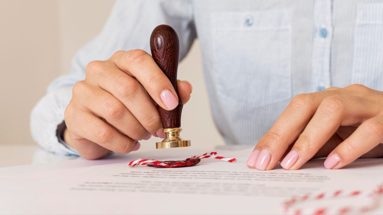 A person pressing a wax seal stamp onto a formal document.