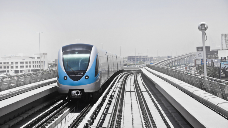 A modern, driverless metro train travelling along an elevated outdoor track