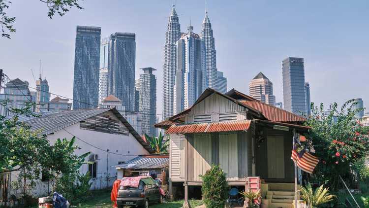Traditional houses with Kuala Lumpur skyline in the background
