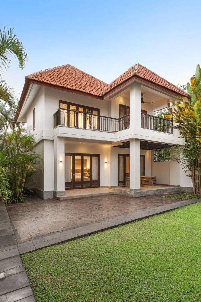 Modern two-story house with a lawn in a tropical setting