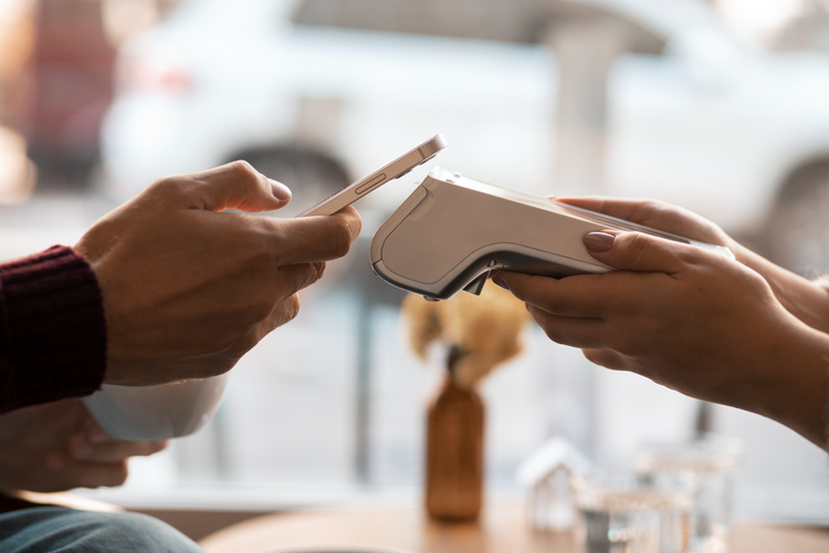 A person holds a phone to a payment terminal held by another person