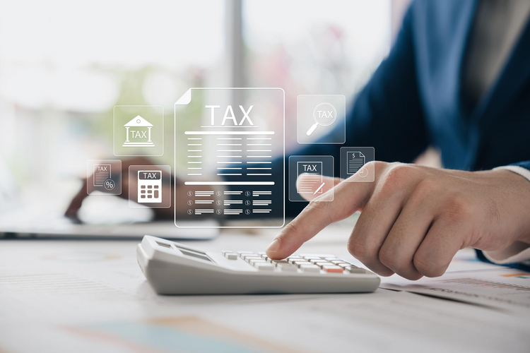 A person in a blue suit using a calculator while a digital "TAX."