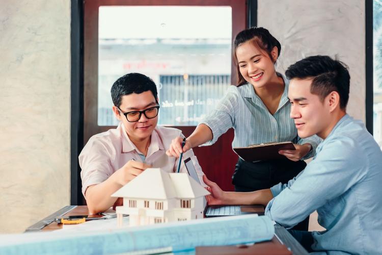 Buyer reviewing a property model and documents while discussing a purchase.
