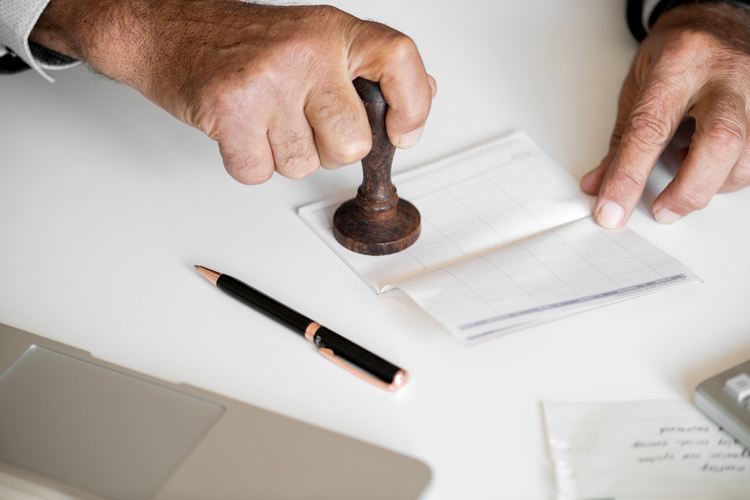 A person uses a wooden stamp on a chequebook