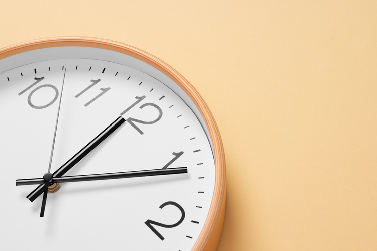 A close-up shot of a round clock with a light wooden frame
