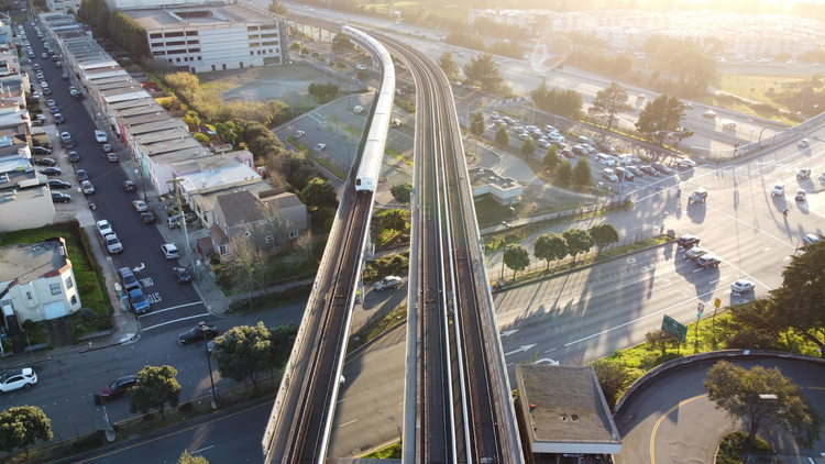 Aerial view of a white commuter train travelling along elevated tracks
