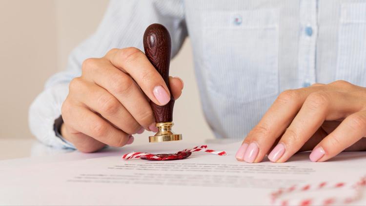 A person is using a wax seal on a blurred contract