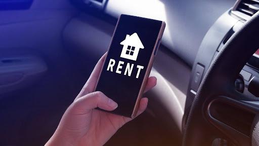 A rent icon is shown on the display of a phone used by a person