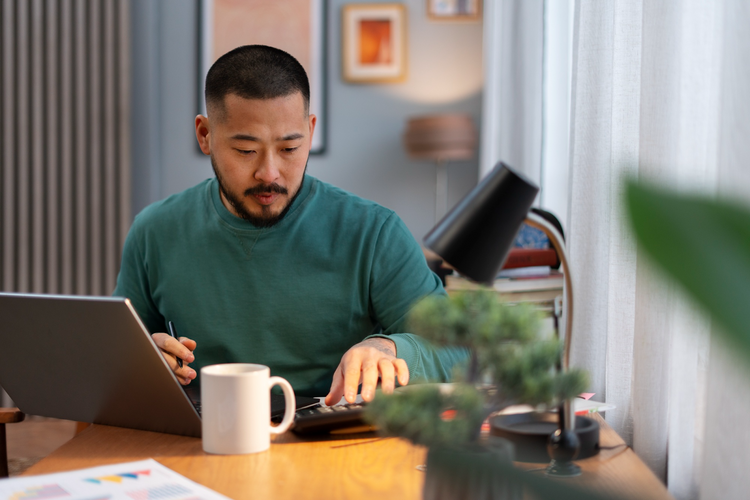 A focused man working at a wooden desk with a laptop.