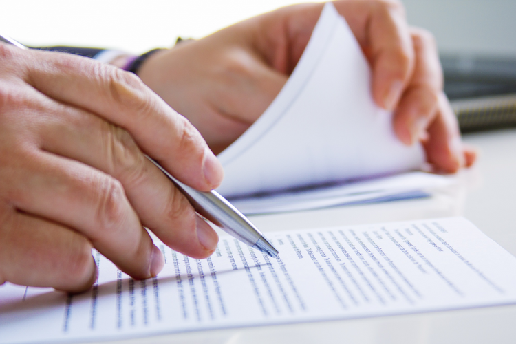  Close-up of hands holding a pen, reviewing and signing
