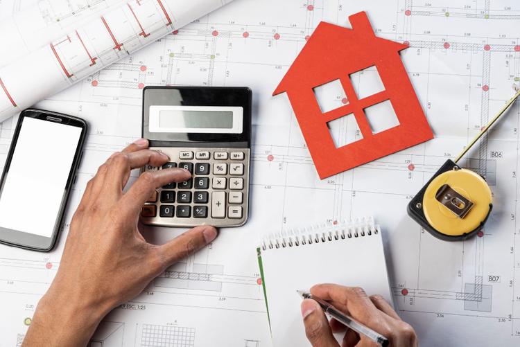 Calculating home renovation costs using a calculator and floor plans.